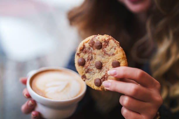 Close up to woman hands with chocolate chip cookie and coffee stock photo