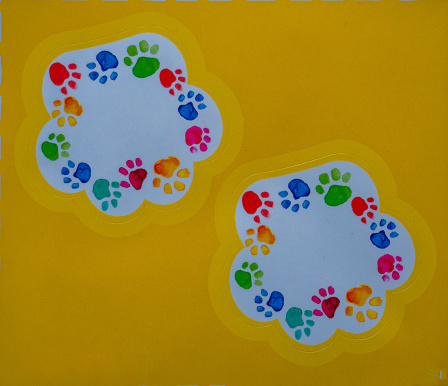 Colored dog paw prints are drawn, on a yellow background. High quality photo