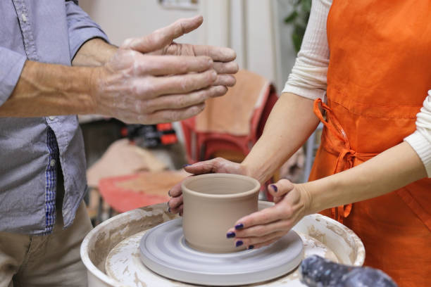 garncarz pomaga kobiecie pracować z kołem ceramicznym - teacher preparation two people teamwork zdjęcia i obrazy z banku zdjęć