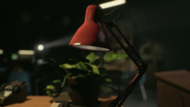 A red lamp sitting on top of a table next to a potted plant