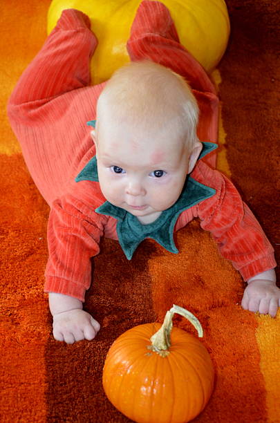 Feliz y sonriente bebé jugando con una pequeña de calabaza - foto de stock