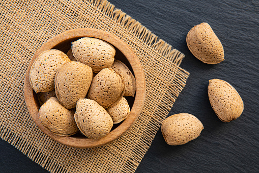 Shelled Almonds in a bowl on stone background.