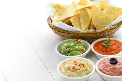 tortilla chips with four championship game dips which are salsa roja, guacamole, taramasalata, and hummus.