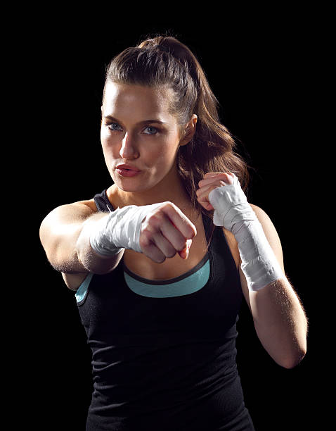 istock Female MMA fighter punching on black background 186302515