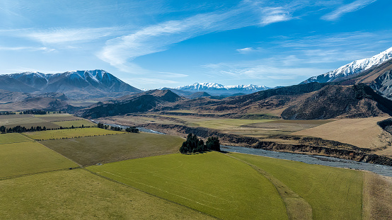 The Porters river flowing through a rural agricultural valley bordered by snow capped mountain  range in the alpine highland country