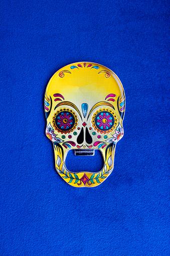 Bottle opener in the shape of a colorful yellow skull painted with floral motifs
