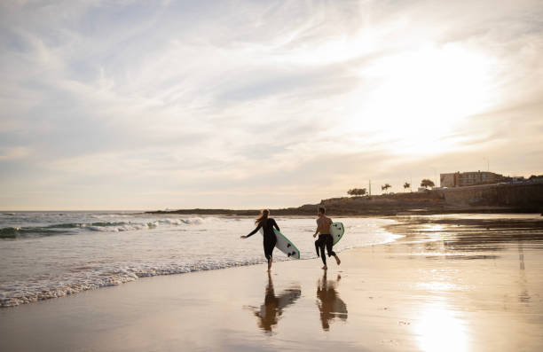 istock Wave Runners. Young Couple With Surfboards Going Into The Ocean 1863051037