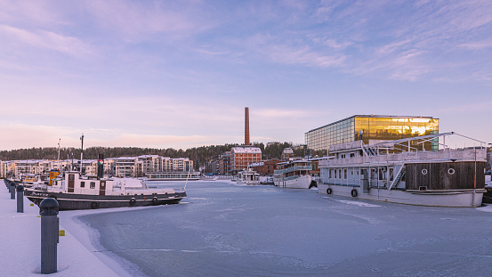 Lahti, Finland. December 17th, 2023. Old steam ships anchored in a frozen lake, in the background sibelius concert hall and old factory.