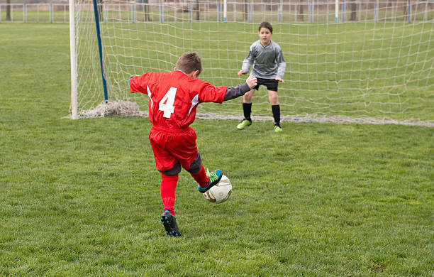 kleine junge shooting at goal - playing field goalie soccer player little boys stock-fotos und bilder