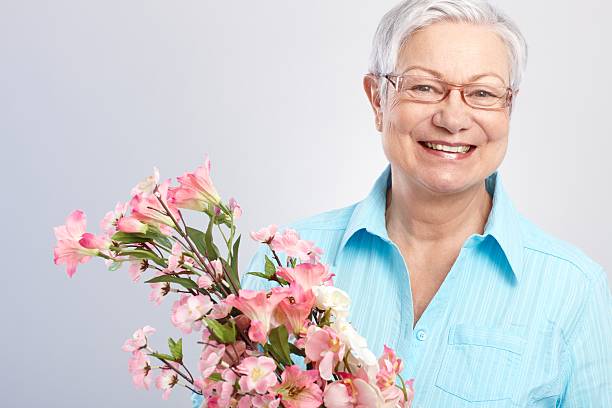istock Elderly lady with flowers smiling 186307641