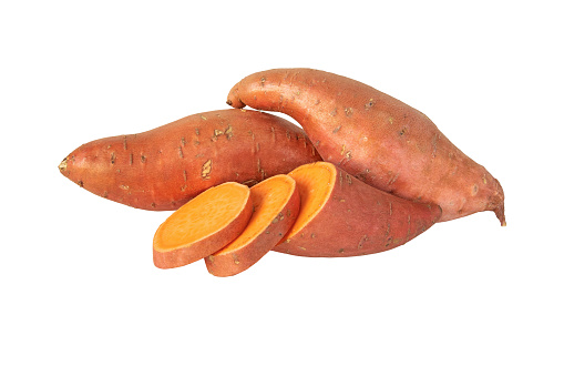 Sweet potato or boniato two whole and one sliced tubes with red skin and yellow flesh isolated on white. Vegetable food staple.