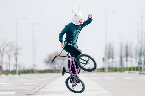 homme avec un masque de licorne faisant du vélo - bmx flatland photos et images de collection