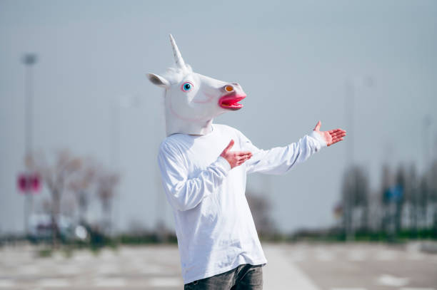 istock Man wearing unicorn mask gesturing to his left side 1863088194