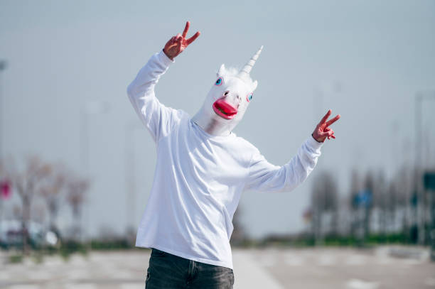 istock Man wearing unicorn mask making victory gesture with fingers 1863088207
