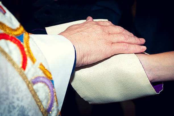 Catholic priest holding his hand on newlyweds' hands, coverred in stole