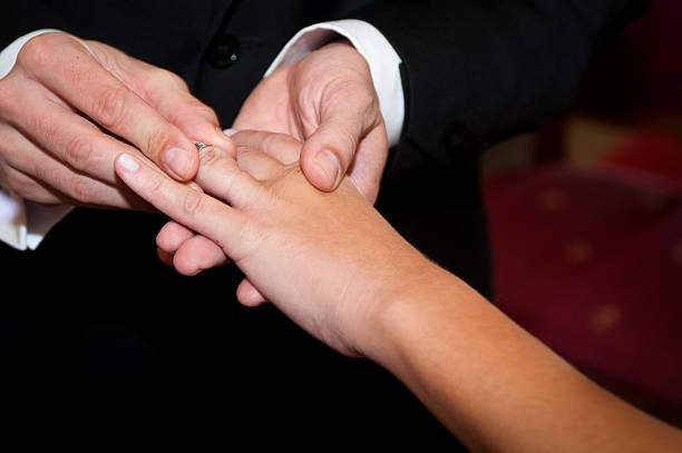 istock Groom putting wedding ring on bride's finger 186309251