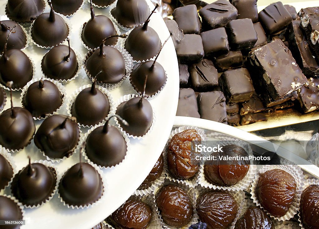 Variety of chocolates Detail of many maraschino cherries covered in dark chocolate, marron glace and dark chocolate nougat Candied Chestnut Stock Photo