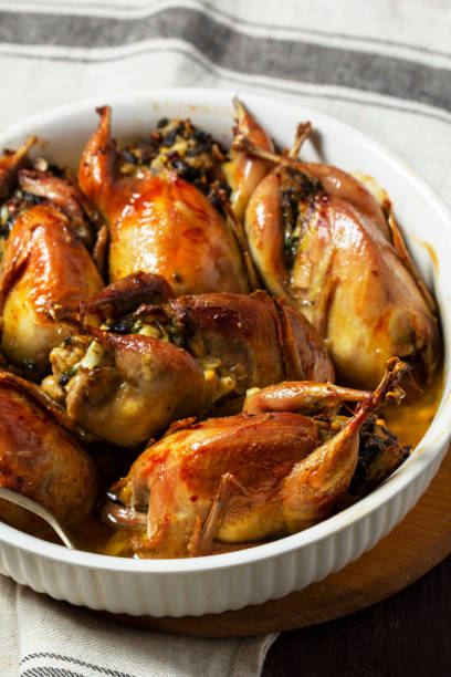 istock Baked quail stuffed with mushrooms, eggs and bread in a ceramic form on a wooden table. 1863169689