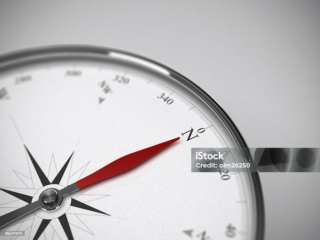 Compass Pointing to the North Measure instrument, compass with red needle pointing to the north. Blur effect focus on the letter N. Grey background Accuracy Stock Photo