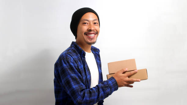 istock Asian man holding a cardboard box while standing against a white background 1863183206
