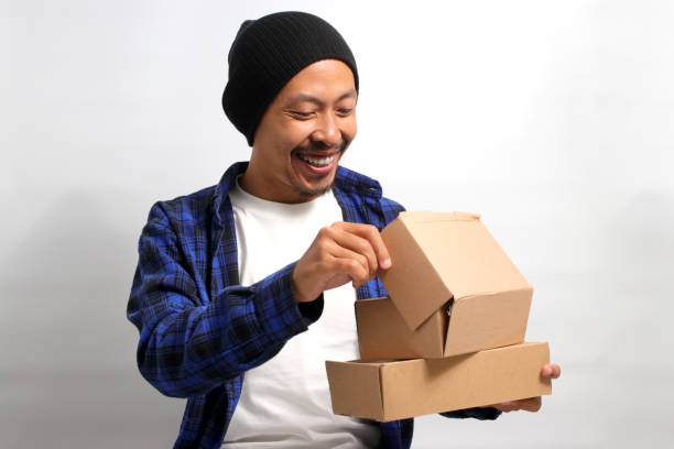 istock Asian man smiles while peering into a package parcel cardboard box 1863184851