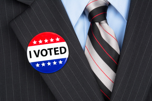 A male voter in his business suit wearing a vote pin on his lapel.
