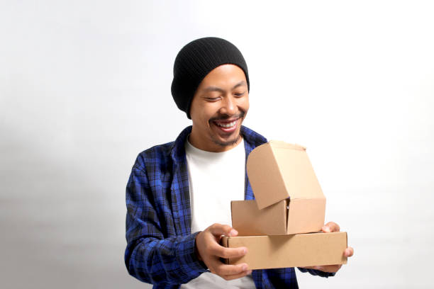 istock Asian man smiles while peering into a package parcel cardboard box 1863196536