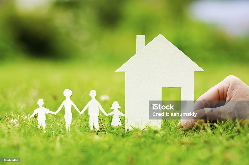 House of paper in hand Hand hold house against green field House Stock Photo