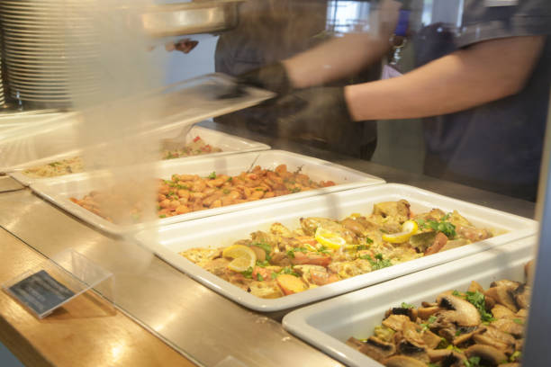 istock Buffet style service - Canteen worker at serving line putting food on the plate 1863208996
