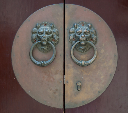 A closeup of an old rusty brass metal handle of an old wooden door