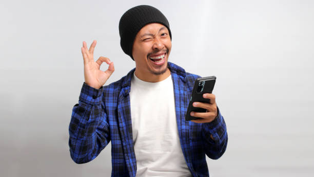 istock Asian man makes OK gesture while holding his phone 1863256171