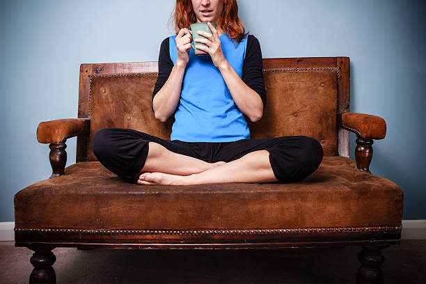 istock Young woman is drinking tea on old sofa 186326139