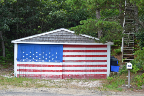 An old garage containing a mural of an American Flag on the front