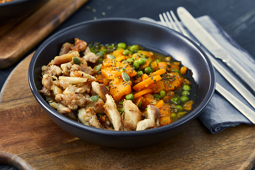Homemade peas with carrot and chicken or beef meat in a pan, on a blue wooden table top