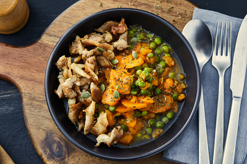 Homemade peas with carrot and fried chicken, on a dark rustic home wooden table top
