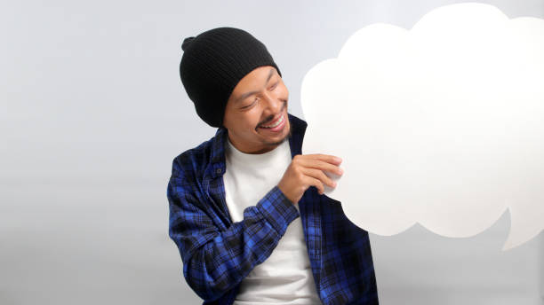 istock Asian man holds speech bubble while standing against a white background 1863278029