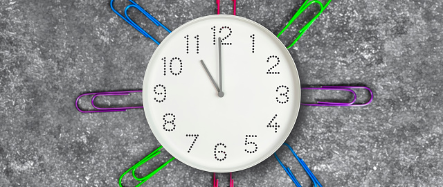 Clock  with white clock face on dark background with colorful paper clips. Concept of study, work, deadline, schedule. Time management.