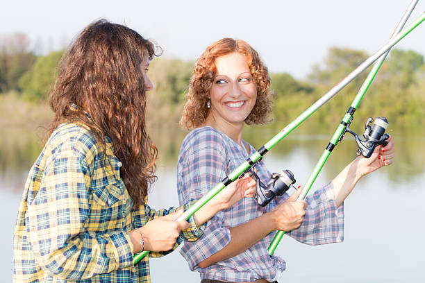 Young women fishing at river Young women fishing at river funny camping signs pictures stock pictures, royalty-free photos & images