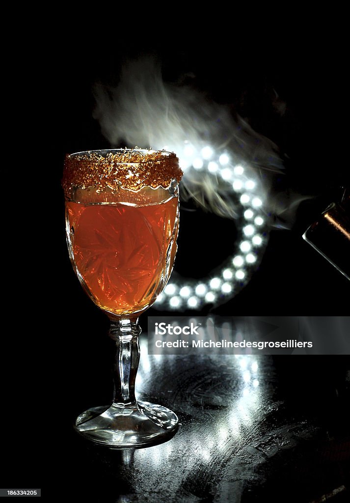 Halloween drink vertical image of glass of orange drink with candies on rim and  smoke and and lights on black Alcohol - Drink Stock Photo