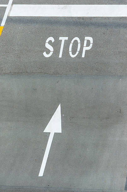 istock White stop sign painted on tarmac with directional arrow. 186336488