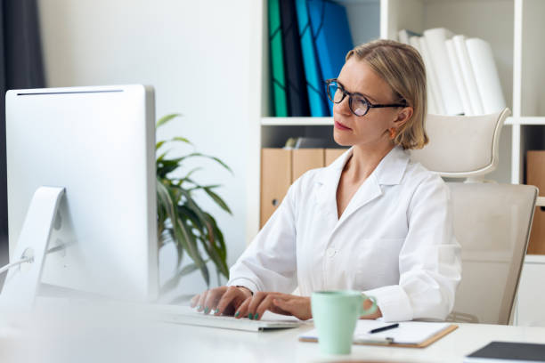 istock Mature female doctor working with computer in the consultation 1863387676