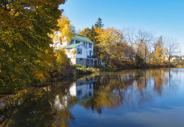 gananoque, canada - 22 October 2022 : historic mansion on fall colored trees and reflection on water surface