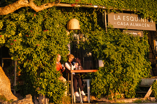 colonia del sacramento, uruguay - november 1 2022: people are sitting at the the counter of a bar in a building covered in ivy during sunset