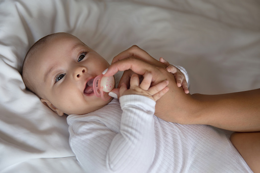 Close-up shot of Cheerful Baby Girl Getting Pacifier from Her Mother