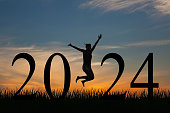 Silhouette of a woman jumping in 2024 on the hill at sunrise