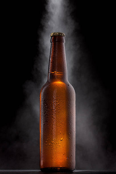 бутылка холодного пива с каплями, мороз и паров на черном - beer bottle beer bottle bottle cap стоковые фото и изображения