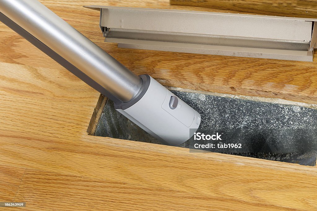 Cleaning inside heating floor vent with Vacuum Cleaner Horizontal photo of vacuum cleaning inside heater floor vent with Red Oak Floors in background Air Duct Stock Photo