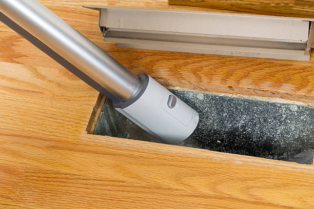 Cleaning inside heating floor vent with Vacuum Cleaner stock photo