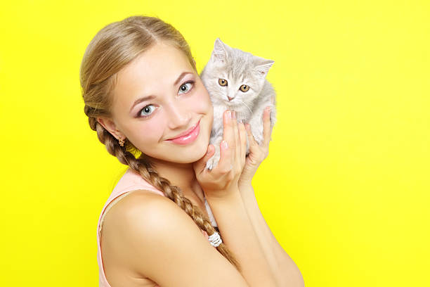 happy young woman with her fluffy cat on black background looking at him, smiling, closeup portrait side view
