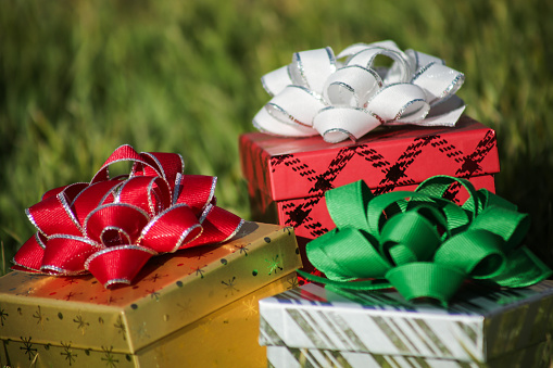 Close-up shot of three multicolored christmas presents sitting on the grass